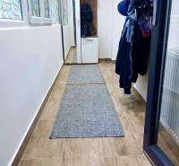 Egy szobás lakás folyosója fa mintázatú csempével, beépített ruhásszekrénnyel.