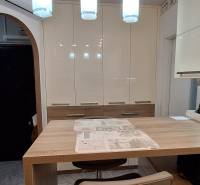 Konyha egy háromszobás lakásban fehér szekrényekkel és faasztallal, fa dekorációjú padlóval.