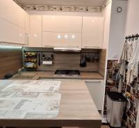 Konyha egy háromszobás lakásban, fa dekor padlóval, modern készülékekkel.