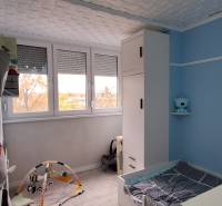 Gyerekszoba kék falakkal, fehér szekrényekkel és gyerek játszószőnyeggel.