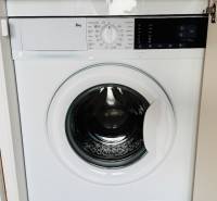 Beépített mosógép egy egyszobás lakásban, fa dekor padlóval.