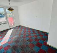 Szoba egy egyszobás lakásban színes padlóval és nagy ablakokkal, kilátással a természetre.