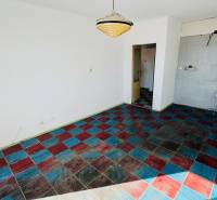 Szoba egy egyszobás lakásban színes csempézett padlóval és függő lámpával.