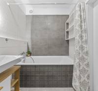 Fürdőszoba egy kétszobás lakásban káddal, mosdóval és zuhanyfüggönnyel, semleges színvilágban.