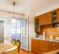 Konyha egy kétszobás lakásban fa szekrényekkel, étkezőasztallal és erkéllyel.