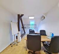 Irodák fa dekor padlóval, asztal, székek, flipchart, víz az asztalon.