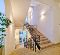 Világos lépcsőház díszes korláttal, amely irodákhoz vezet.