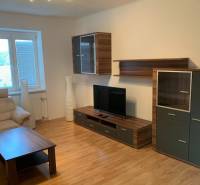 Nappali egy kétszobás lakásban fa dekorációjú padlóval és kényelmes kanapéval.