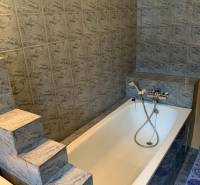 Fürdőszoba egy kétszobás lakásban káddal és márványcsempével burkolva.