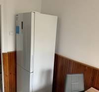 Konyha egy kétszobás lakásban hűtőszekrénnyel, sötét burkolattal és étkezősarokkal.