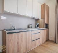 Konyha egy kétszobás lakásban, fa dekorációjú padlóval és világos konyhabútorral.