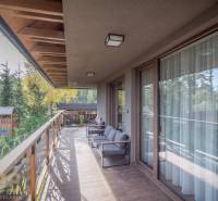 A Tátralomnici kétszobás lakás erkélye fa dekorációjú padlóval és kilátással a zöldre.