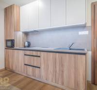 Konyhaszekrény fa dekorral, beépített készülékek és fa dekor padló egy 2 szobás lakásban.