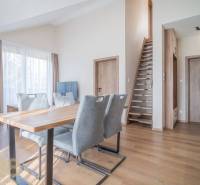 Nappali étkezőasztallal és lépcsővel egy kétszobás lakásban, fa dekoros padlóval.