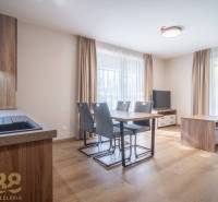 Tágas belső tér egy kétszobás lakásban fa dekorációjú padlóval és étkezőasztallal.