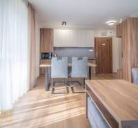 2 szobás lakás belső tere konyhasarokkal, szürke székekkel és fa mintázatú padlóval.