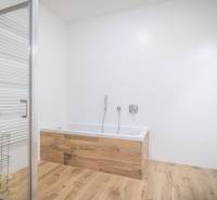 Fürdőszoba káddal és fa dekorációjú padlóval egy kétszobás lakásban.