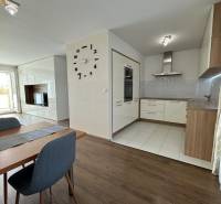 Étkező tér egy 4 szobás lakásban fa mintázatú padlóval és háttérben a konyhával.