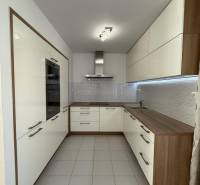 Konyha egy 4 szobás lakásban világos szekrényekkel és padlócsempével.