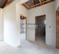 Családi ház belső tere vakolatlan falakkal és látható tetőszerkezettel.