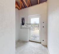 Világos szoba egy családi házban betonpadlóval és üvegajtókkal.