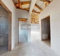 Családi ház befejezetlen belső tere fa tetőszerkezettel és nyitott helyiségekkel.