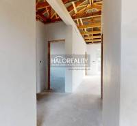 Családi ház belső tere tetőszerkezettel és fehér vakolt falakkal.