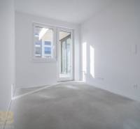 Világos szoba fehér falakkal és nagy ablakokkal egy háromszobás lakásban.