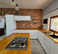 Konyha családi házban téglafallal, fa kiegészítőkkel és fa dekorációjú padlóval.