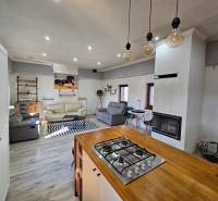 Családi ház belső tere kandallóval és konyhával, fa dekorációjú padlóval.