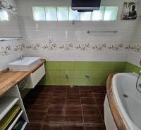 Fürdőszoba családi házban fa dekor padlóval, mosdóval és káddal.