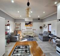 Nappali családi házban kanapékkal, konyhával és fa dekorációjú padlóval.