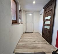 Folyosó egy családi házban fa dekor padlóval és világos falakkal.