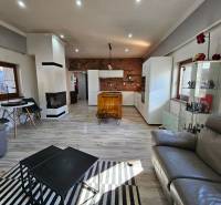 Nappali egy családi házban kandallóval, fa dekorációval és ülőgarnitúrákkal.