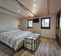 Hálószoba családi házban ággyal, dekoratív bőrönddel és fa mintázatú padlóval.