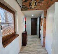 Téglafalú folyosó órával, fa dekorációjú padlóval, fa bútorokkal.