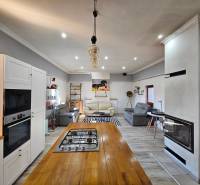 Konyha családi házban tűzhellyel, fehér szekrényekkel és fa mintázatú padlóval.