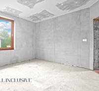 Egy családi ház befejezetlen szobája betonpadlóval és nagy ablakkal.