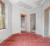 Családi ház piros csempével, vakolt falakkal és három nyitott átjáróval.