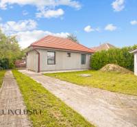 Családi ház Bátorkeszin, gyepes udvarral, beton járdával és piros tetővel.