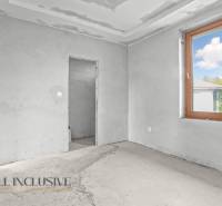 Családi ház belső tere befejezetlen falakkal és nagy ablakkal.