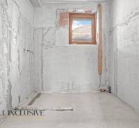 Fürdőszoba felújítása családi házban, vakolatlan betonfalak, egyetlen kis ablak.