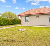 Családi ház Bátorkeszin piros tetővel, zöld gyep és bokrok veszik körül.