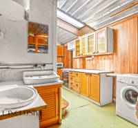 Konyha egy családi házban fa szekrényekkel, mosogatóval és mosógéppel.