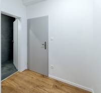 Folyosó szürke ajtókkal, sötét csempékkel rendelkező fürdőszobával és fa dekorációjú padlóval.