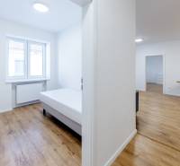 Világos, 3 szobás lakás fa dekorációjú ággyal és padlóval.