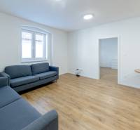 Nappali kék kanapékkal és fa dekorációjú padlón lévő asztallal.