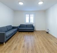 Nappali egy háromszobás lakásban kanapéval és fa dekorációjú padlóval.