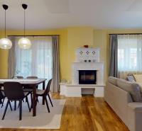 Nappali kandallóval, étkezőasztallal és fa dekorációjú padlóval egy családi házban.