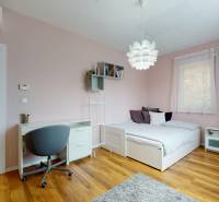 Hálószoba családi házban íróasztallal, ággyal és fa dekorációjú padlóval.